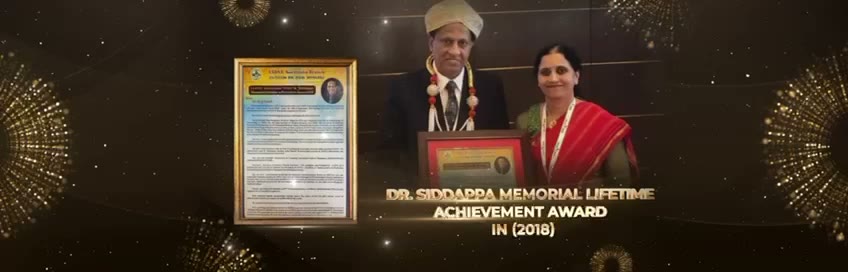 Dr. Satish in a turban and garland standing with a woman in a red saree, holding a framed award, beside the citation certificate.